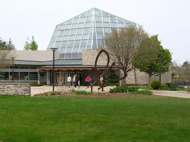 A large metal butterfly sculpture in front of a high glass dome