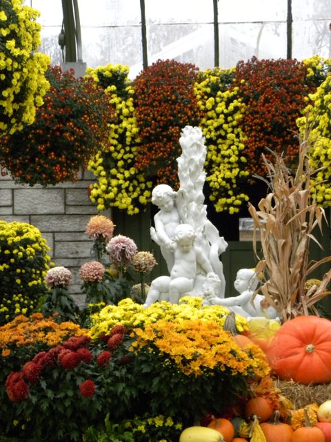 White marble fountain featuring little babies with yellow, orange mums