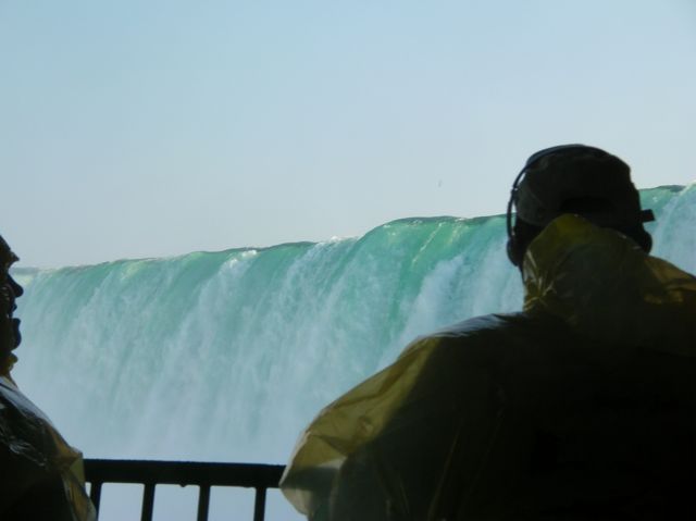 Two silhouettes and the green crest of Canadian Falls above them